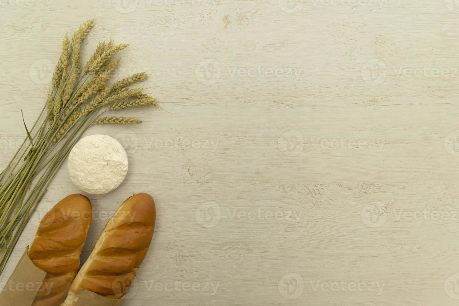 Homemade fresh bread with wheat ear on white wood table. photo