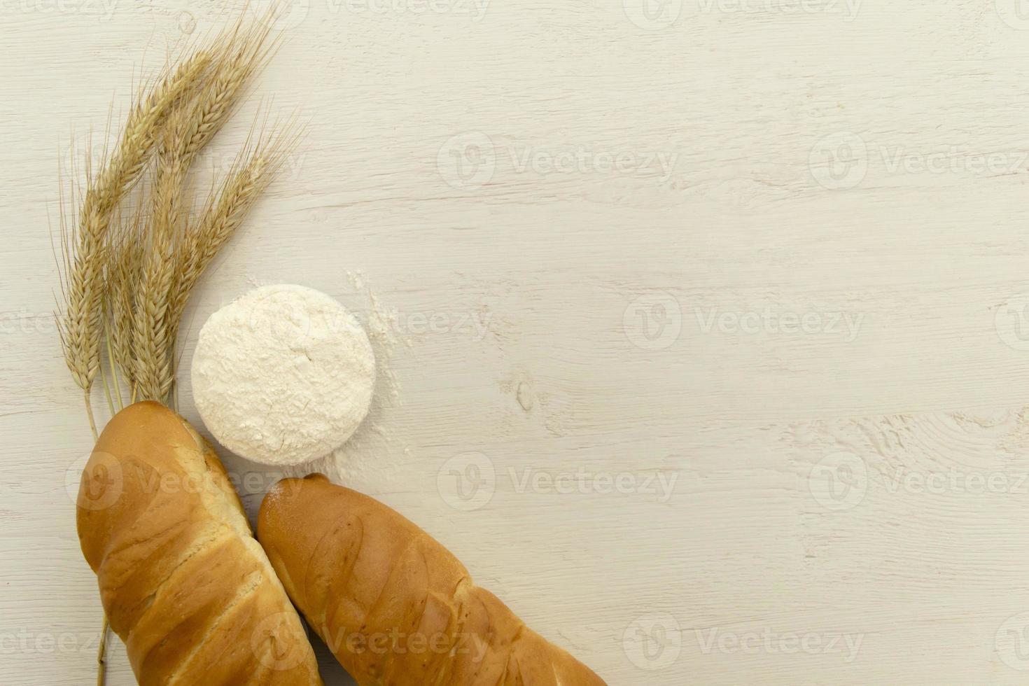 Homemade fresh bread with wheat ear on white wood table. photo