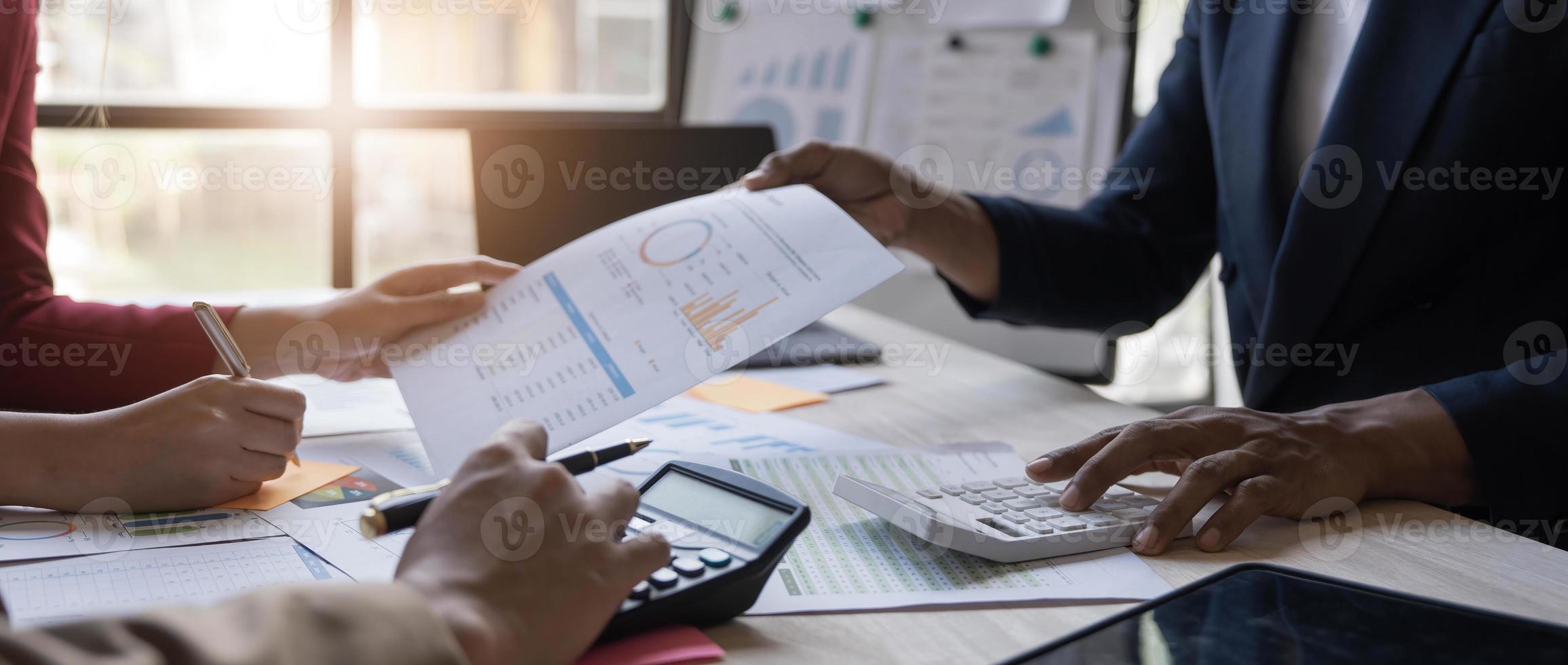 gente de negocios reunida usando computadora portátil, calculadora, cuaderno, papel gráfico del mercado de valores para planes de análisis para mejorar la calidad el próximo mes. conferencia discusión concepto corporativo foto