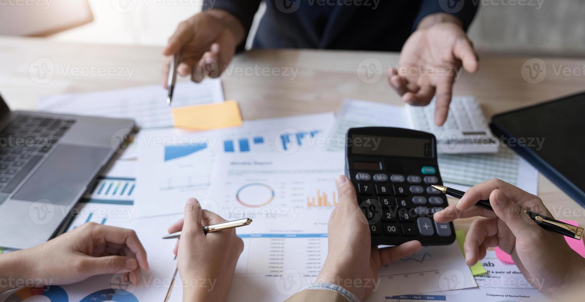 gente de negocios reunida usando computadora portátil, calculadora, cuaderno, papel gráfico del mercado de valores para planes de análisis para mejorar la calidad el próximo mes. conferencia discusión concepto corporativo foto