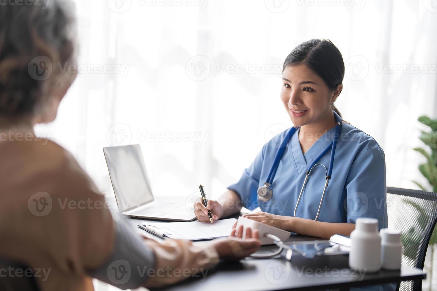 Nurse measuring blood pressure of senior woman patient in retirement home. Home caregiver doing routine checkup of a mature female patient. photo