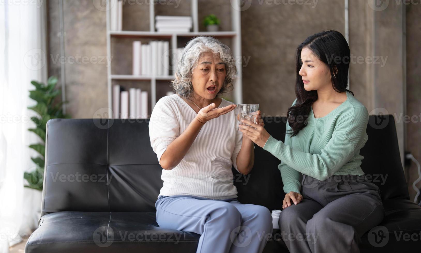 joven asiática cuidando y dando un vaso de agua y tomando medicamentos diarios o suplementos vitamínicos, atención médica para ancianos y abuela. foto