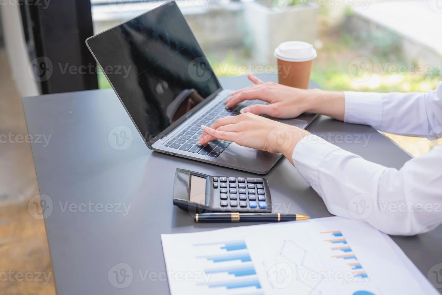 Marketing, Financial, Accounting, Planning, business women analyze company results and profits with graph statistics. Use a laptop computer and a calculator to calculate the company is balance. photo