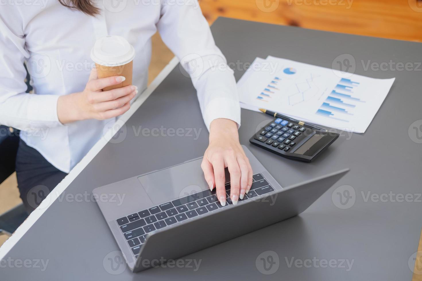 Marketing, Financial, Accounting, Planning, business women analyze company results and profits with graph statistics. Use a laptop computer and a calculator to calculate the company is balance. photo