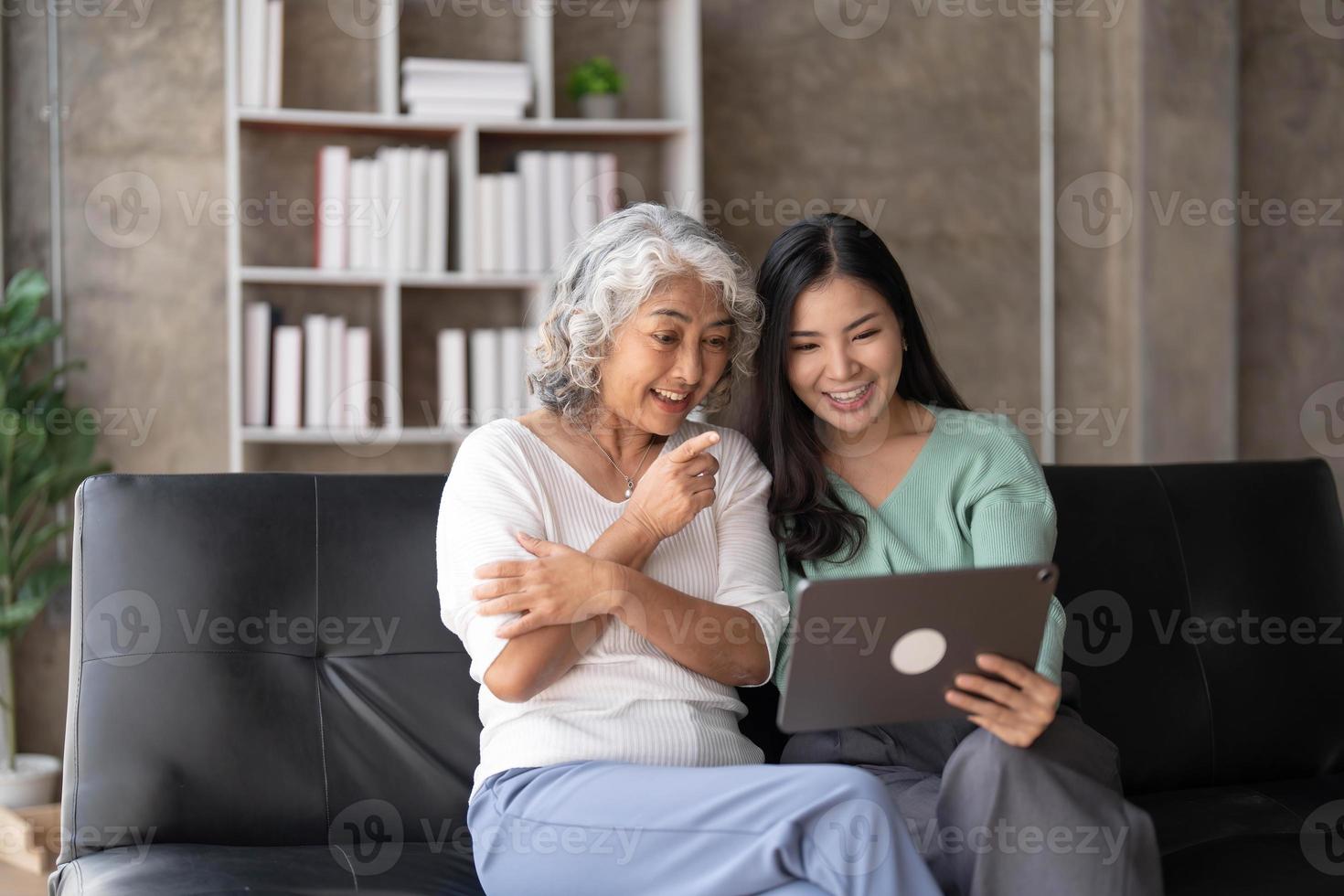 Mature mother grown up daughter sit on couch in living room hold on lap pc looking at screen watching movie film, using device make video call, shopping via e-commerce website, girl teach mom concept photo