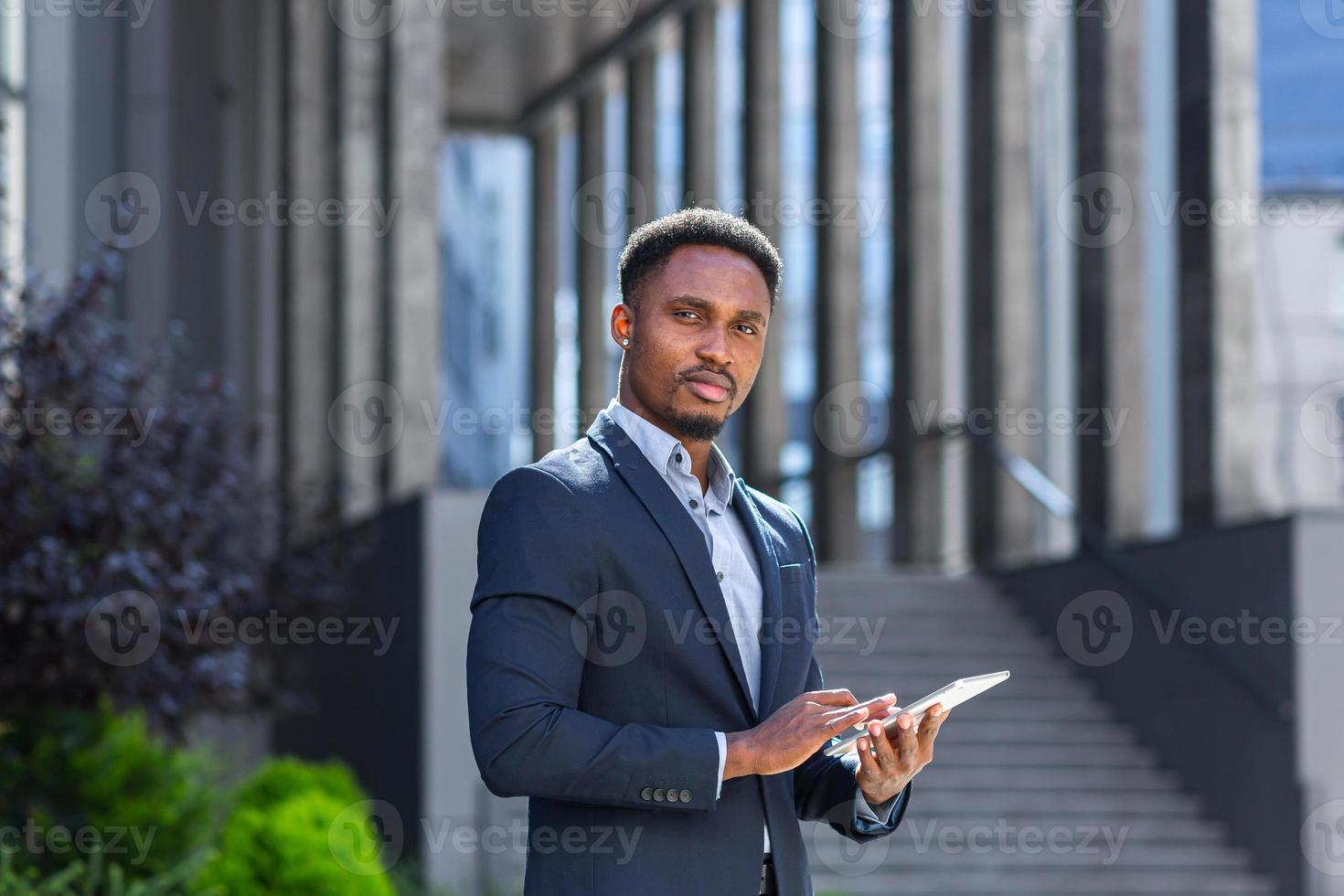 joven hombre de negocios afroamericano en traje de negocios formal de pie trabajando con tableta foto