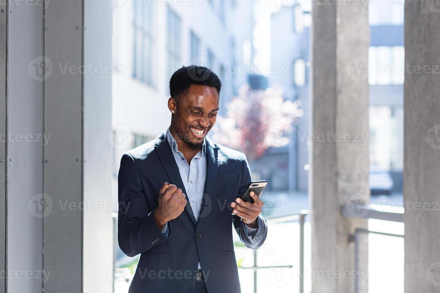 Exited African American Businessman Celebrating Achievement looking at Smartphone photo