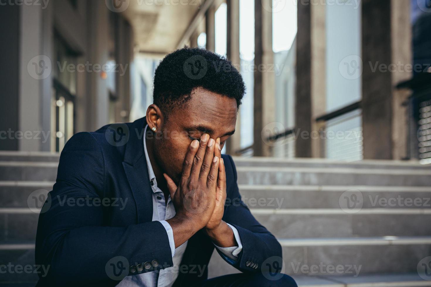 trabajador de oficina masculino cansado después del trabajo, afroamericano tiene dolor de cabeza severo, sentado foto