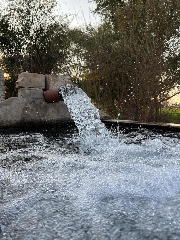 flujo de agua de riego desde la tubería hasta el canal para campos agrícolas foto