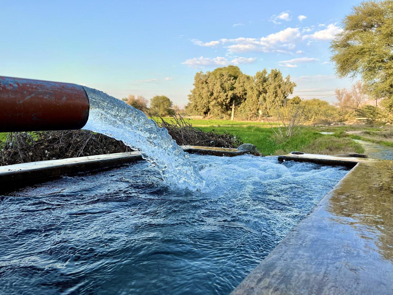 flujo de agua de riego desde la tubería hasta el canal para campos agrícolas foto