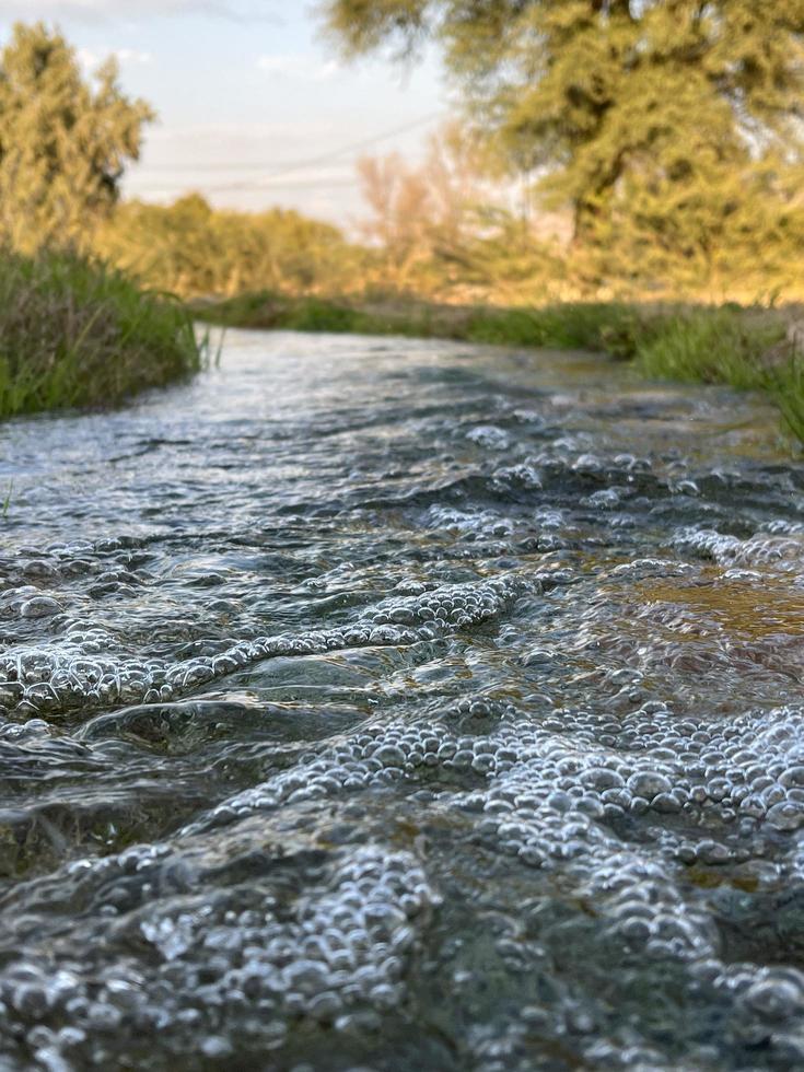 flujo de agua de riego desde la tubería hasta el canal para campos agrícolas foto