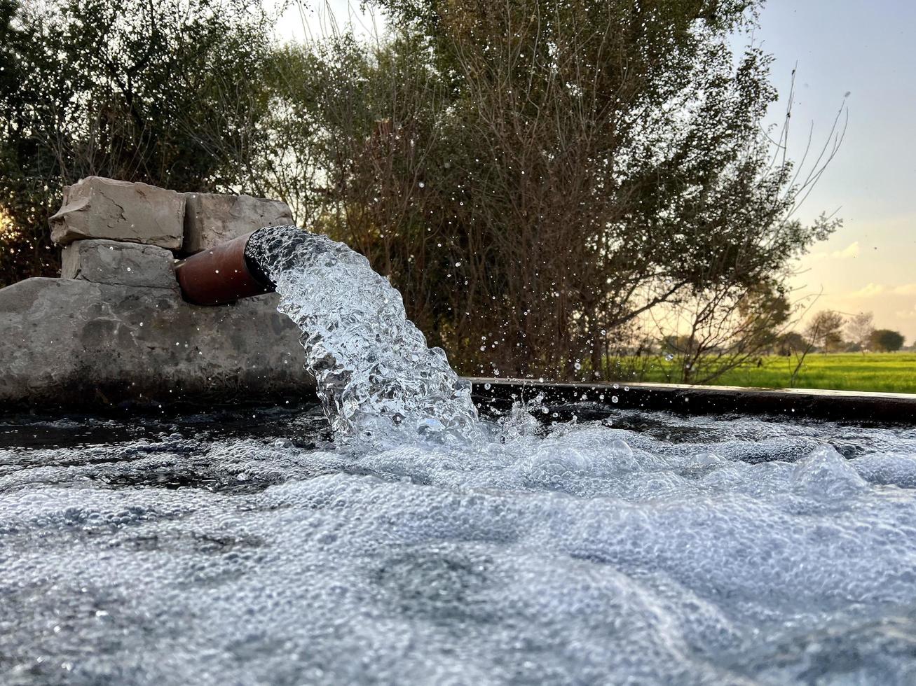 flujo de agua de riego desde la tubería hasta el canal para campos agrícolas foto