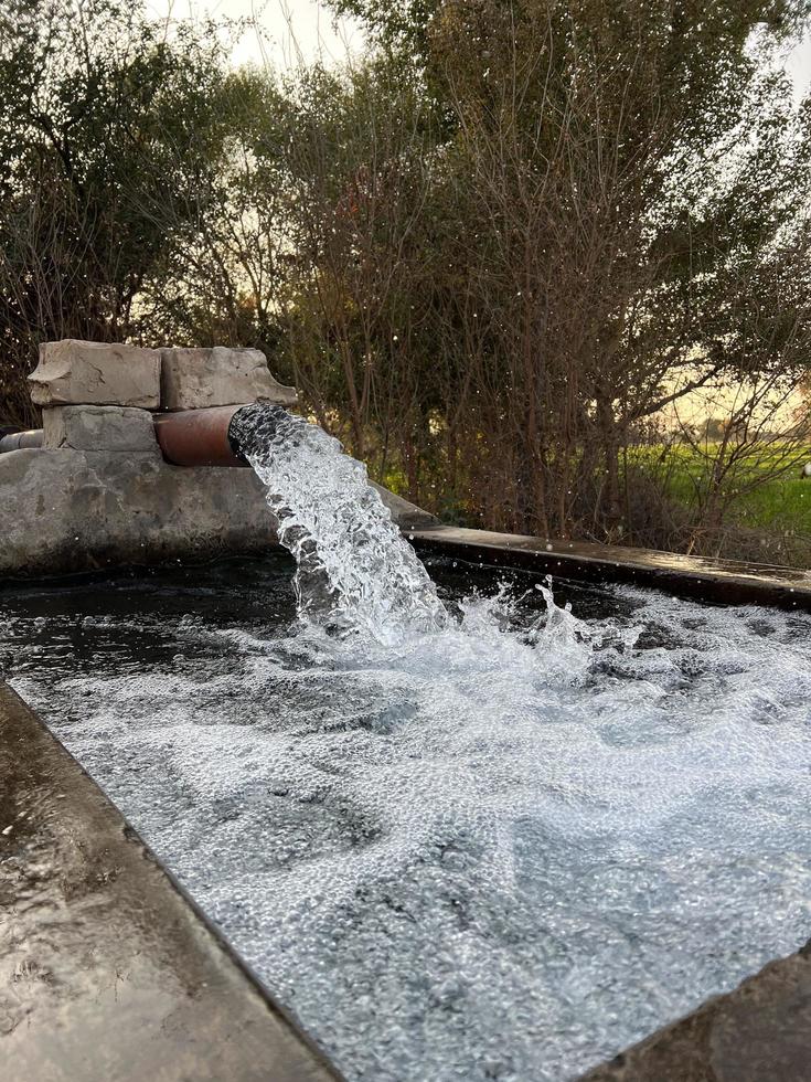Irrigation water flow from pipe to canal for agriculture fields photo