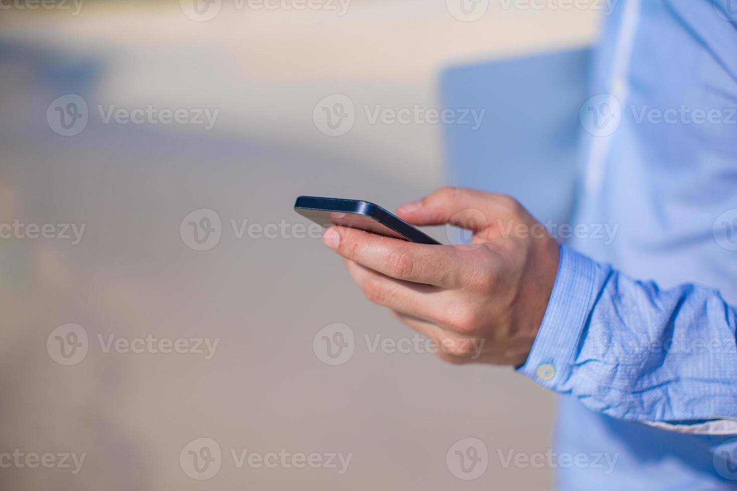 Close up telephone in male hand at tropical beach photo