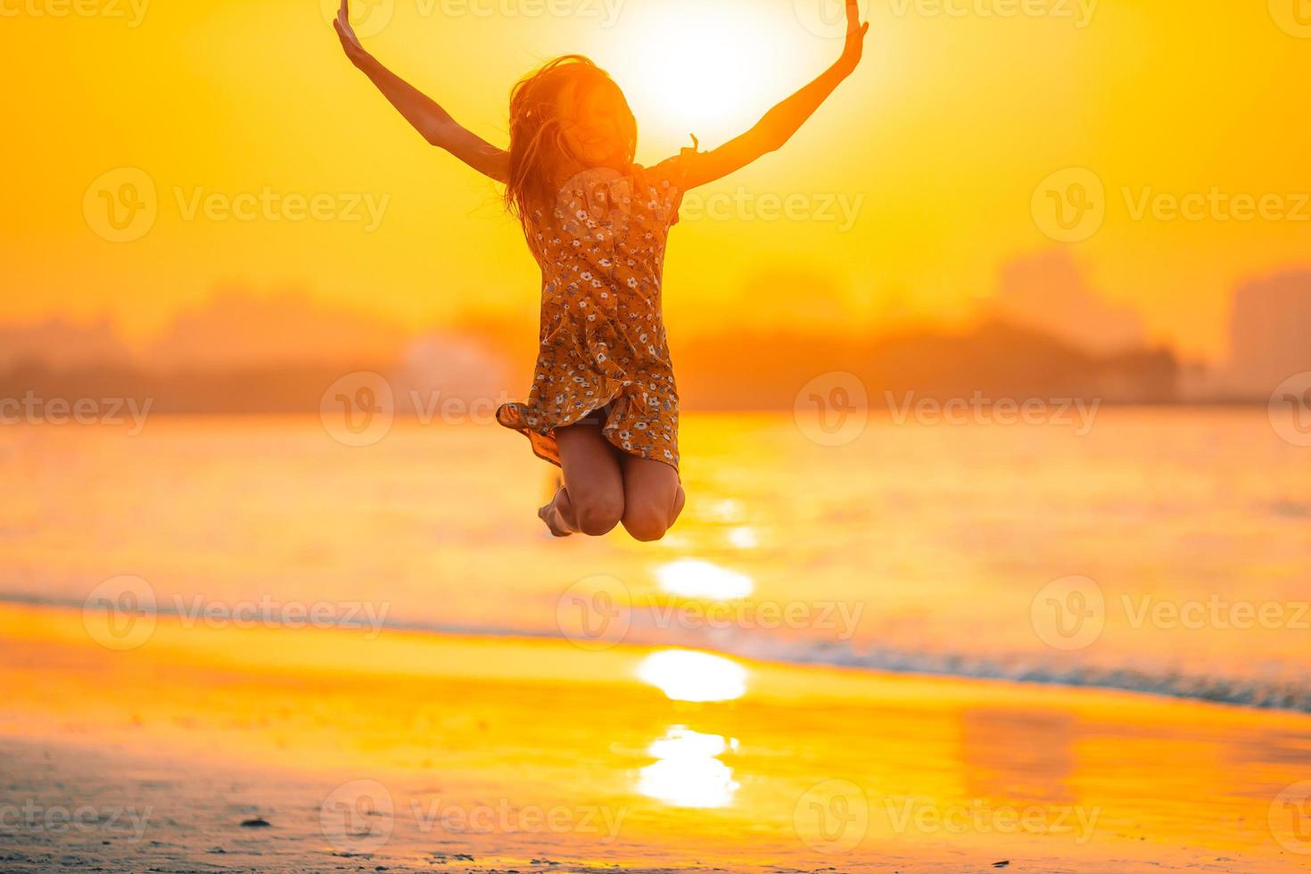 Adorable happy little girl on white beach at sunset. photo