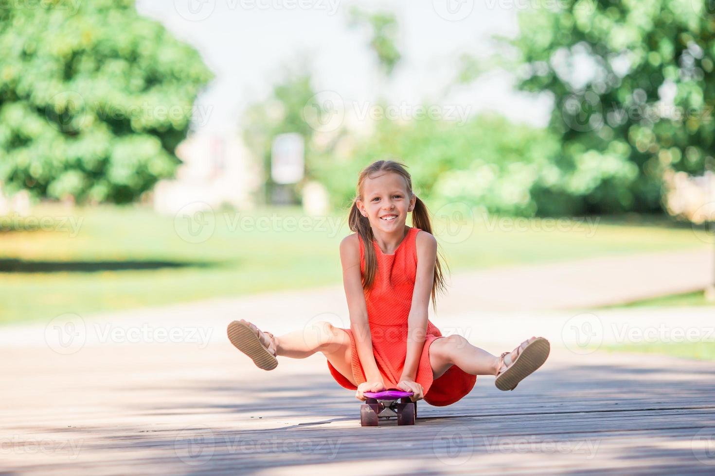 Adorable kid riding skateboard in summer park. photo