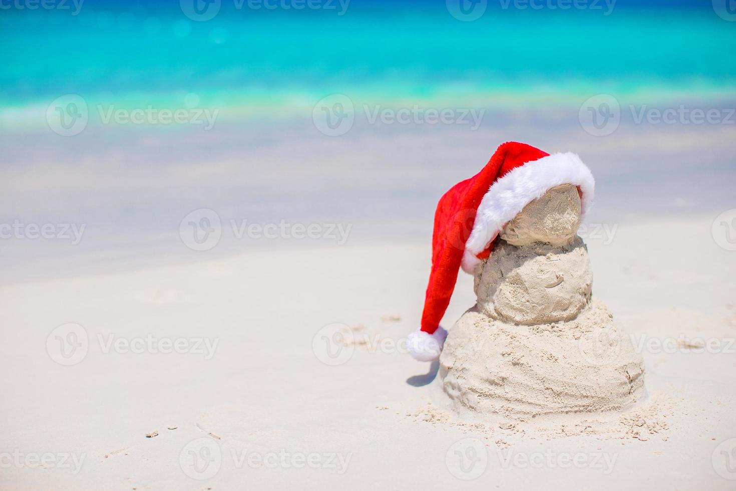 Little sandy snowman with red Santa Hat on white Caribbean beach photo