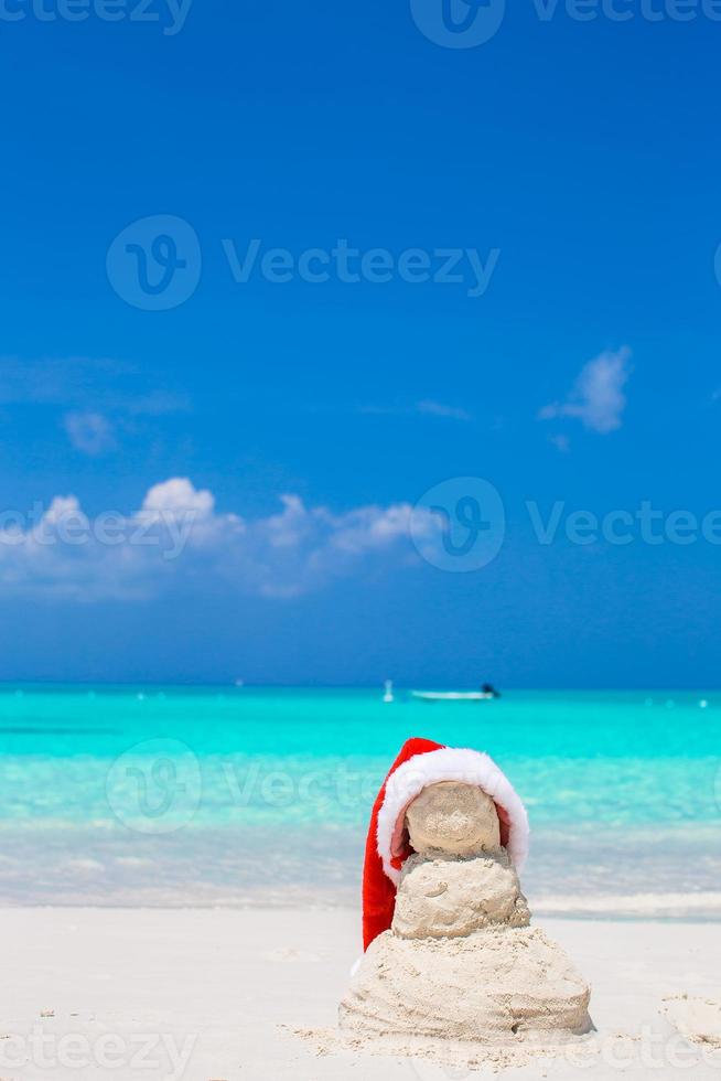 Little sandy snowman with red Santa Hat on white Caribbean beach photo