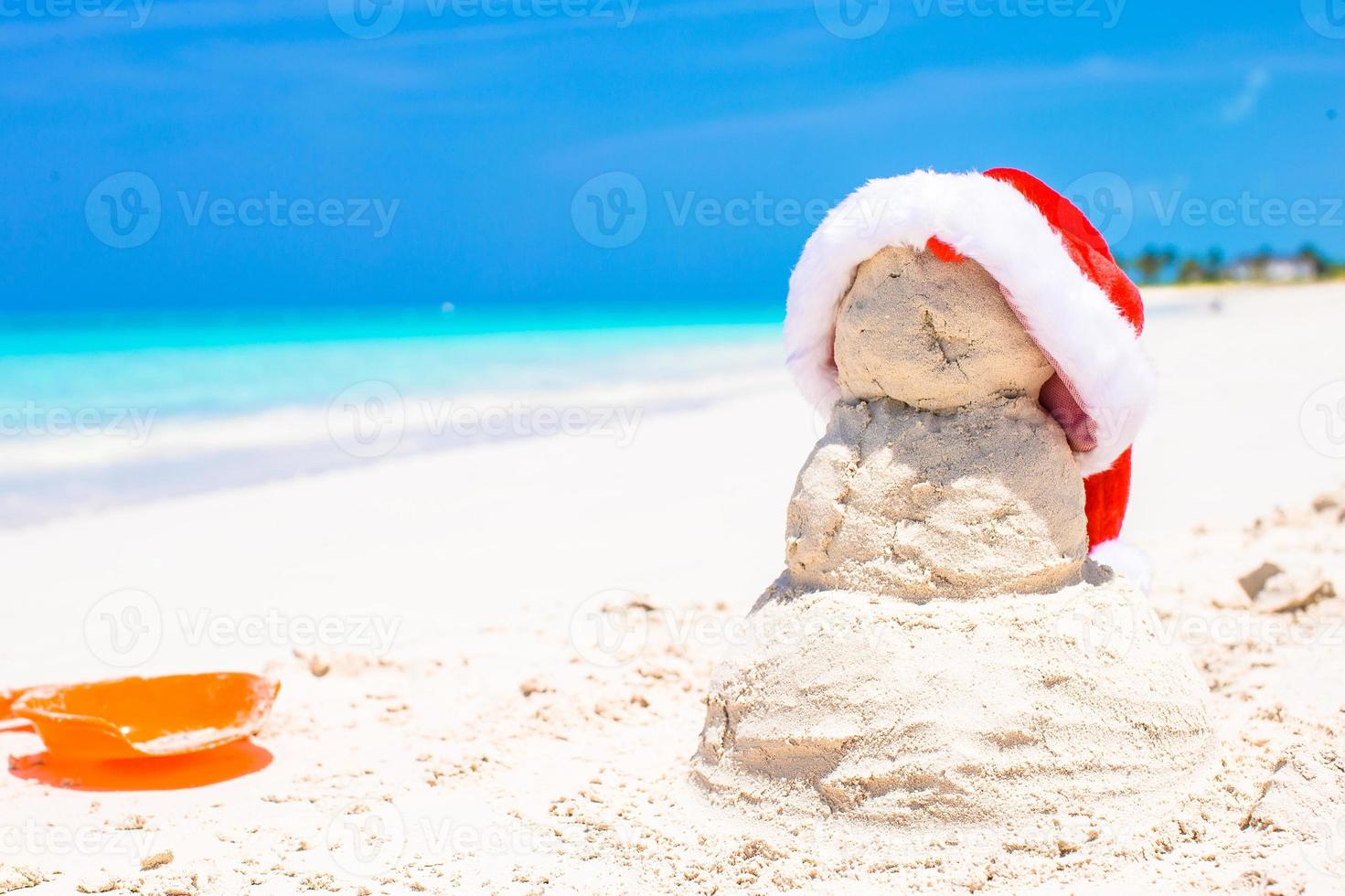 Sandy snowman with red Santa Hat on white Caribbean beach photo