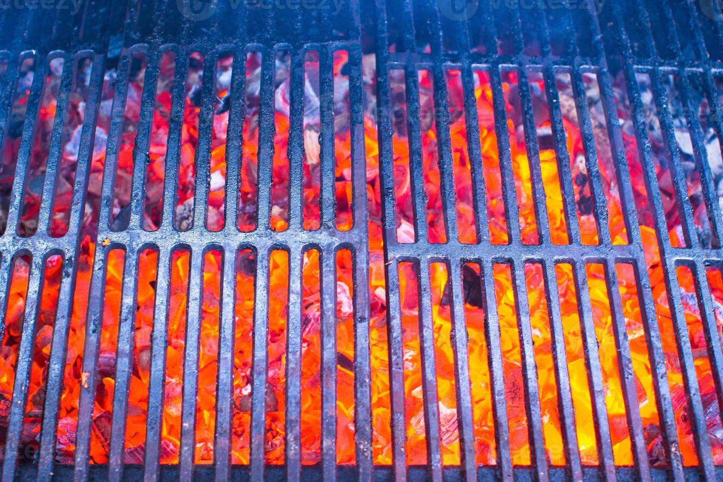 Empty black cast iron grill with hot red glowing coals photo