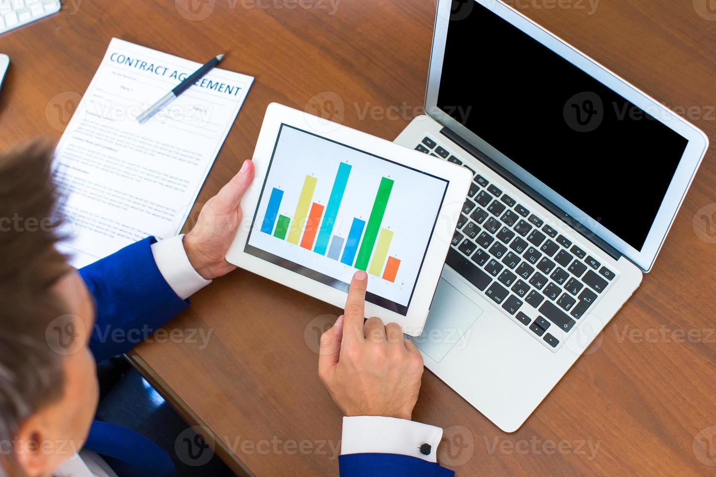 Young businessman working with modern devices, digital tablet computer and cellphone photo
