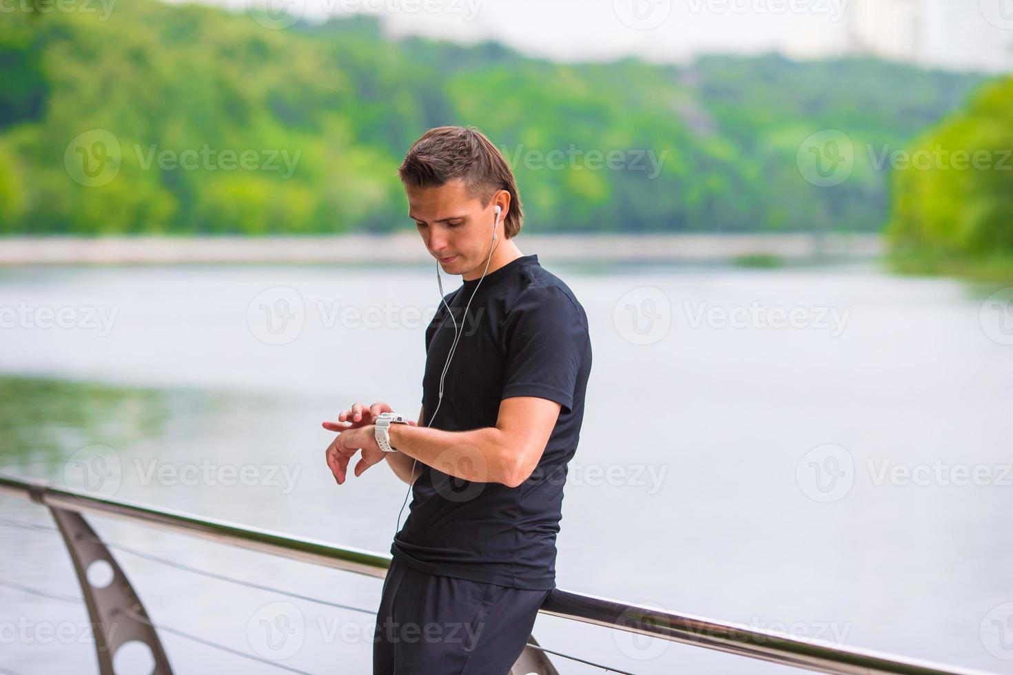 corredor mirando el monitor de frecuencia cardíaca del reloj inteligente que tiene un descanso mientras corre foto