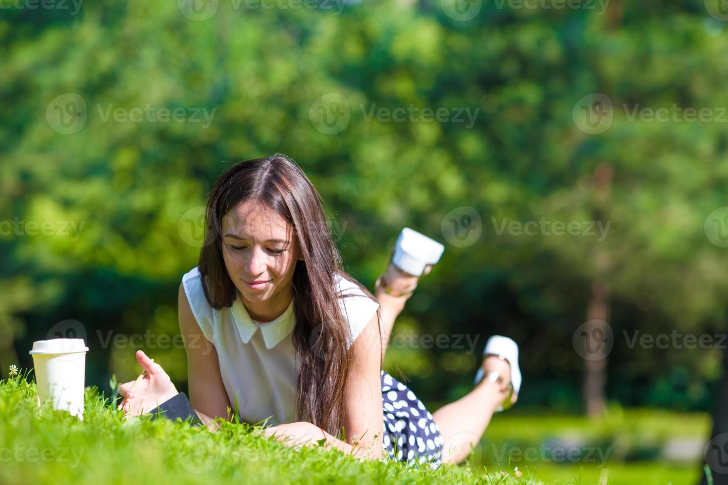 Young girl writing in her notebook outside at park photo