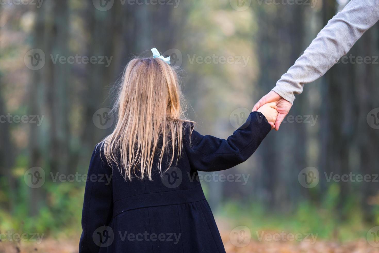 Little adorable girl with dad in autumn park at warm day photo