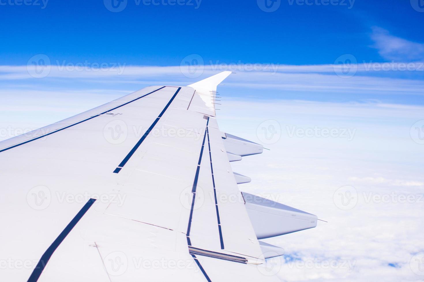 Wing of an airplane flying above the clouds photo