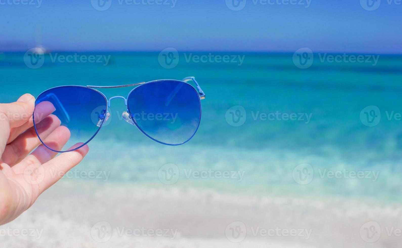 Close up of colorful blue sunglasses on tropical beach photo