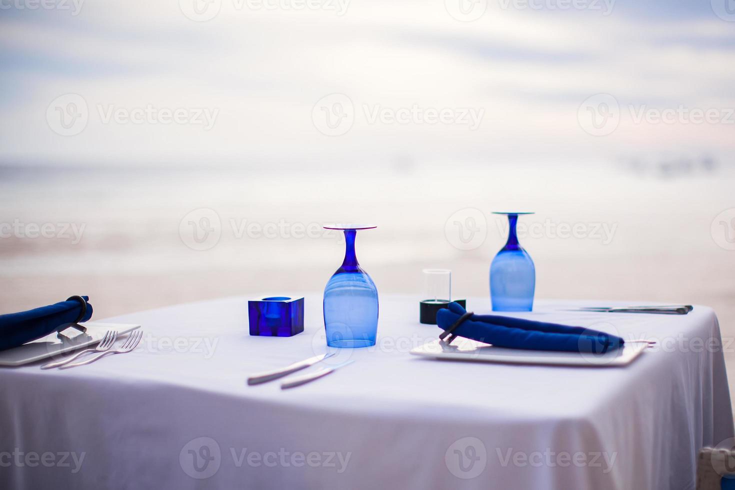 Summer empty open air table set for dinner on white beach photo