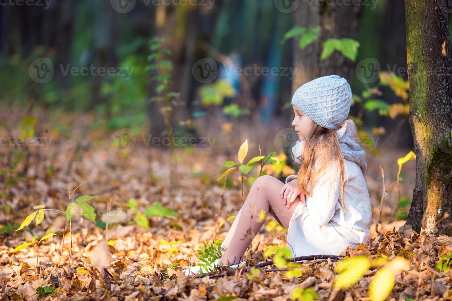 adorable niña con hojas de otoño en el hermoso parque foto