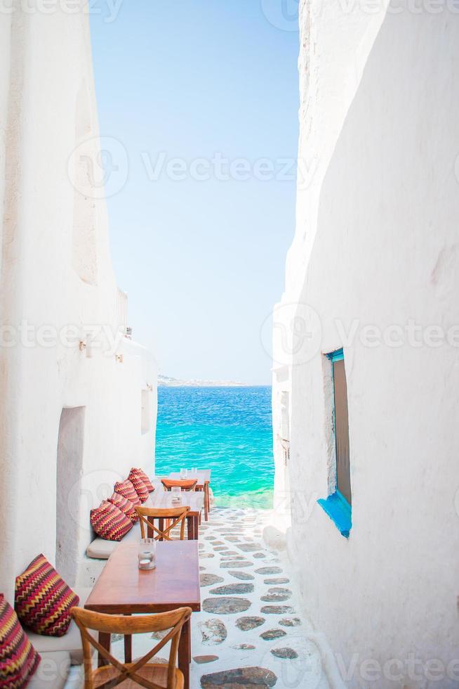 Benches with pillows in a typical greek outdoor cafe in Mykonos with amazing sea view on Cyclades islands photo