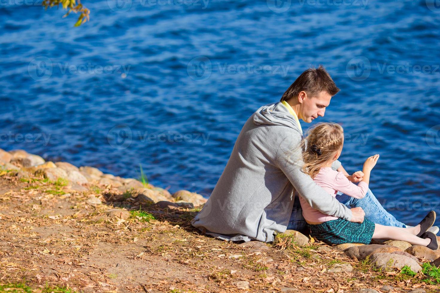 niña adorable con padre feliz cerca del río en el cálido día de otoño foto