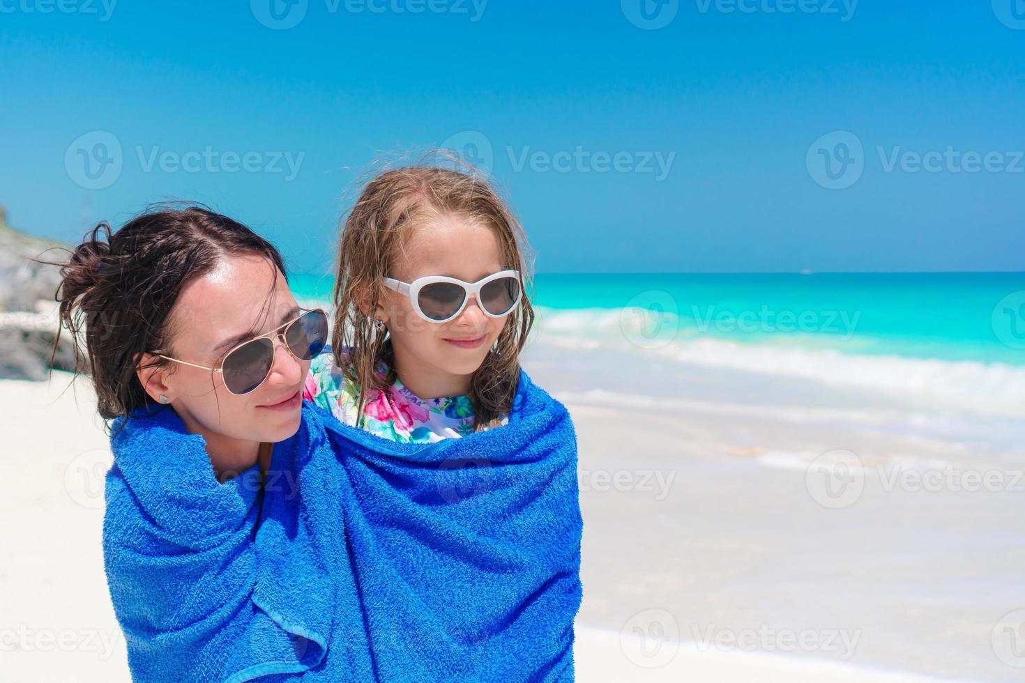 Happy mother and little girl on the beach vacation. Family in towel on the seashore photo