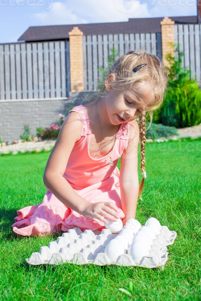 Adorable little girl preparing for Easter with a tray of white eggs photo