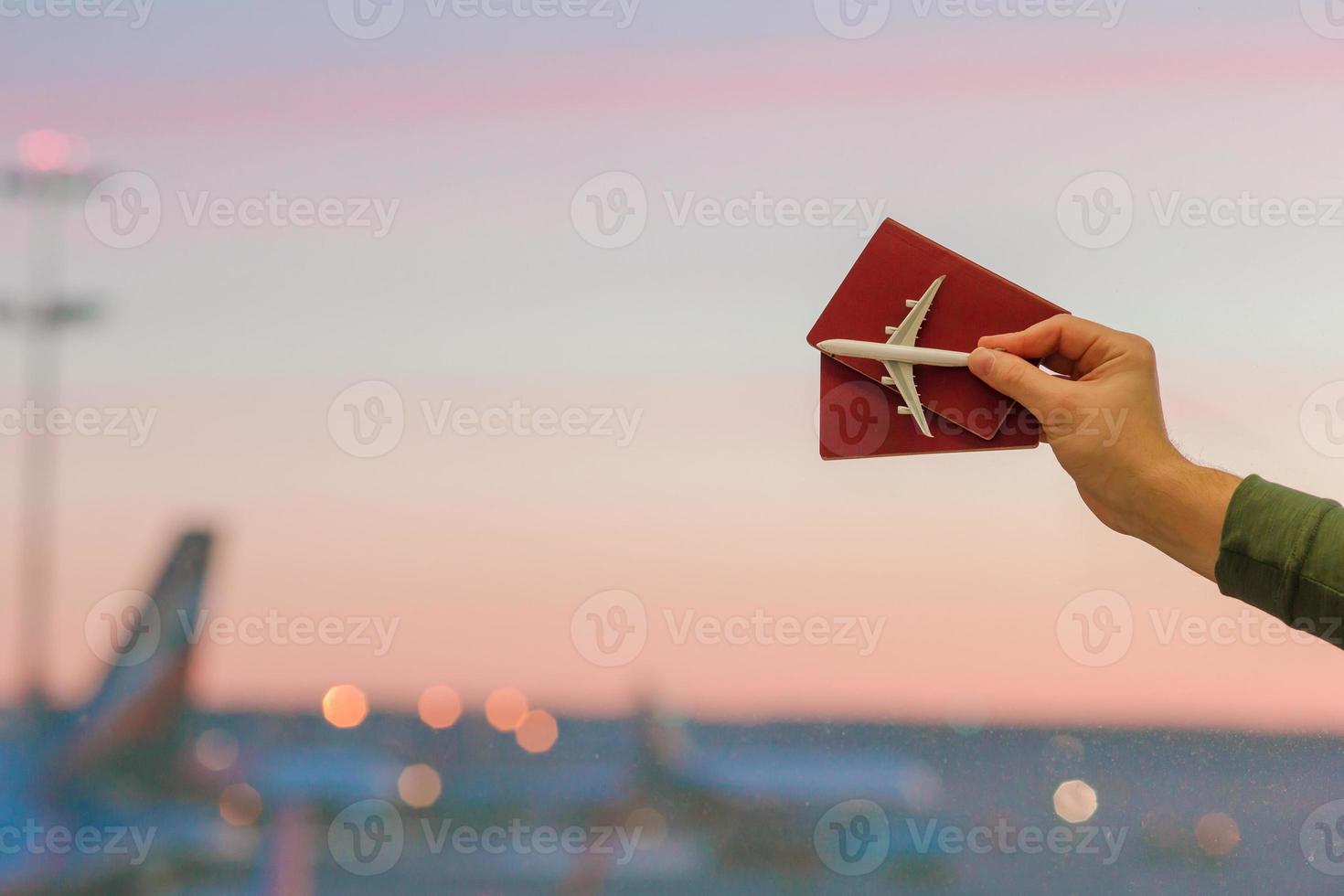 Closeup an airplane model toy and passports at the airport background big window at dawn photo