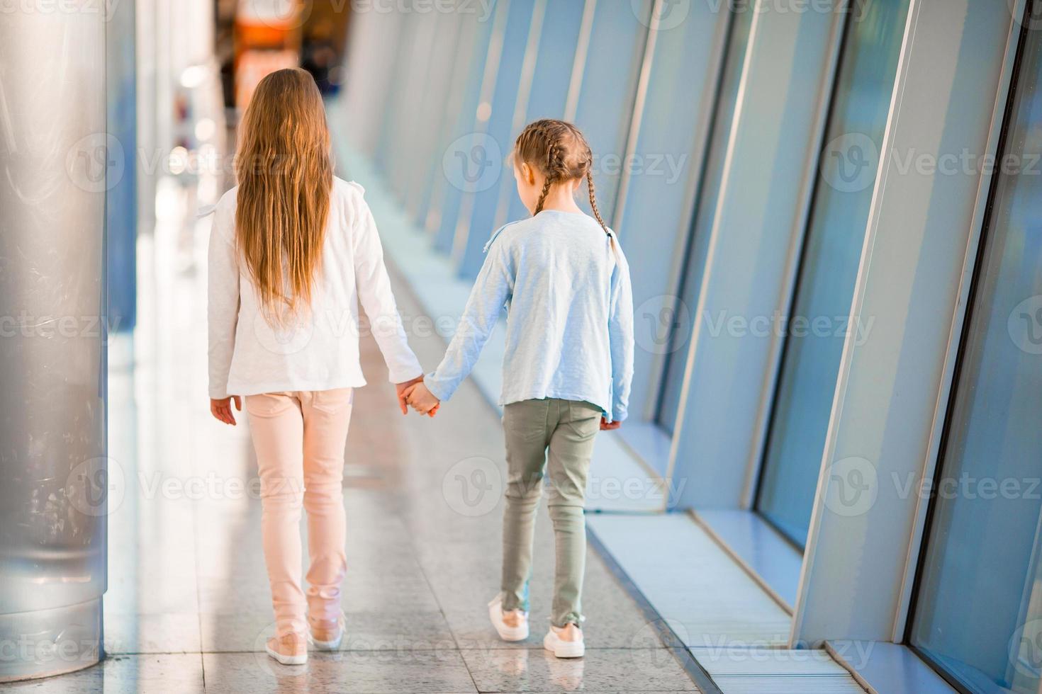 Little adorable girls in airport near big window photo