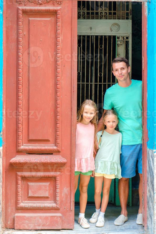 Portrait of happy family looking out door at old apartments in Havana photo