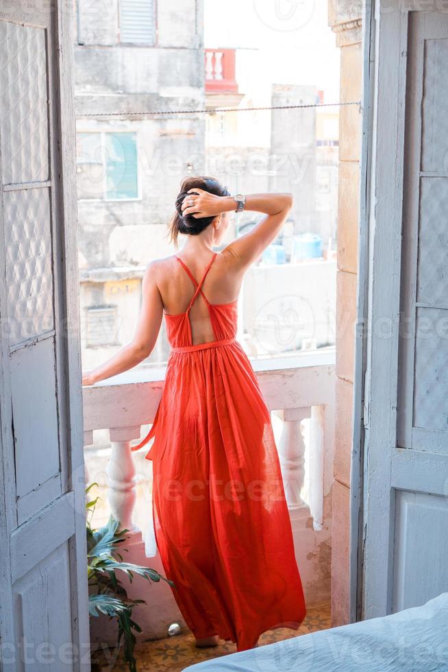 mujer hermosa joven en vestido rojo en el viejo balcón en apartamento en la habana vieja, cuba. foto