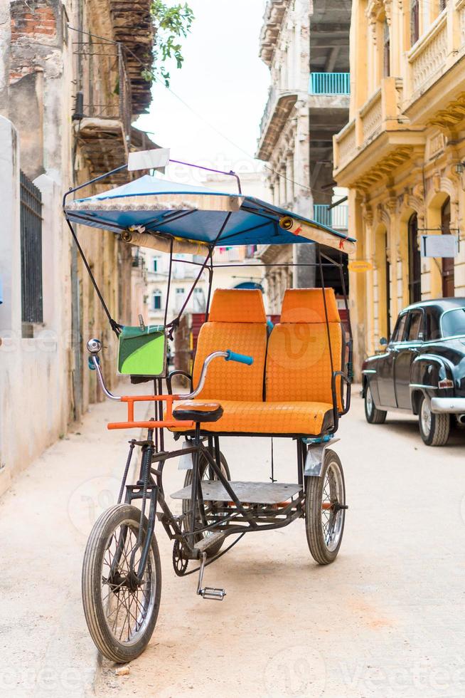 Taxi cubano bicicleta estacionada frente a coloridas casas coloniales foto