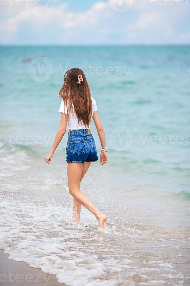 Back. view of happy girl running on the beach photo