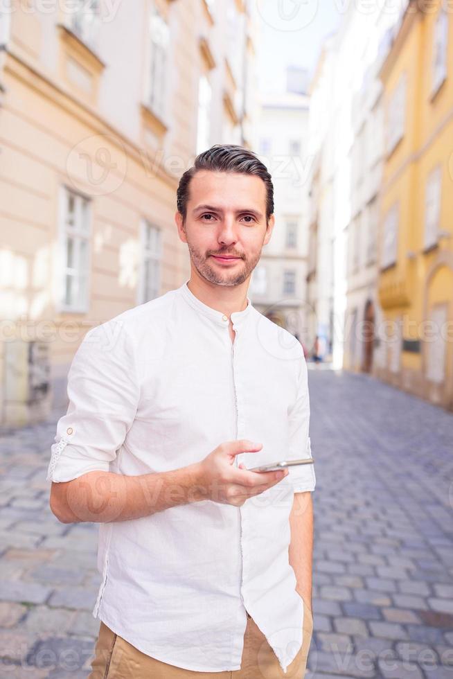 Man tourist with cellphone in Europe street. Caucasian boy looking at camera outdoor photo