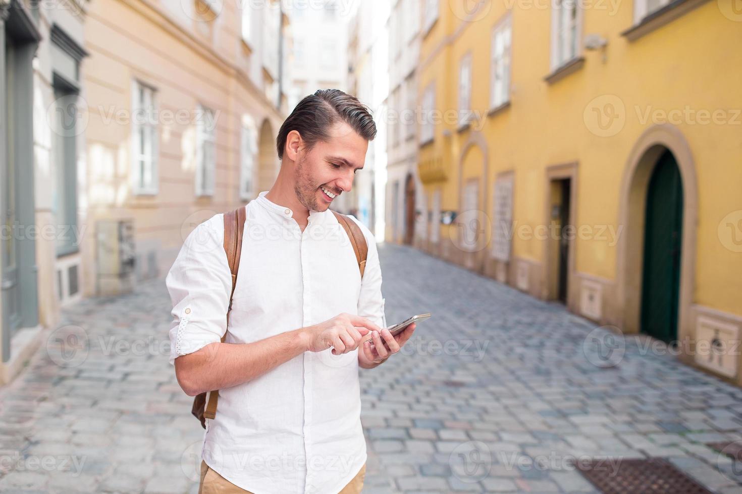 Man tourist with backpack in Europe street. Caucasian boy looking with map of European city. photo