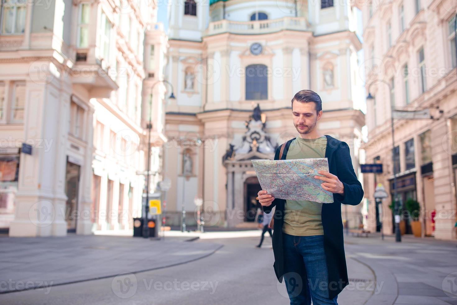Man tourist with a city map and backpack in Europe street. Caucasian boy looking with map of European city. photo
