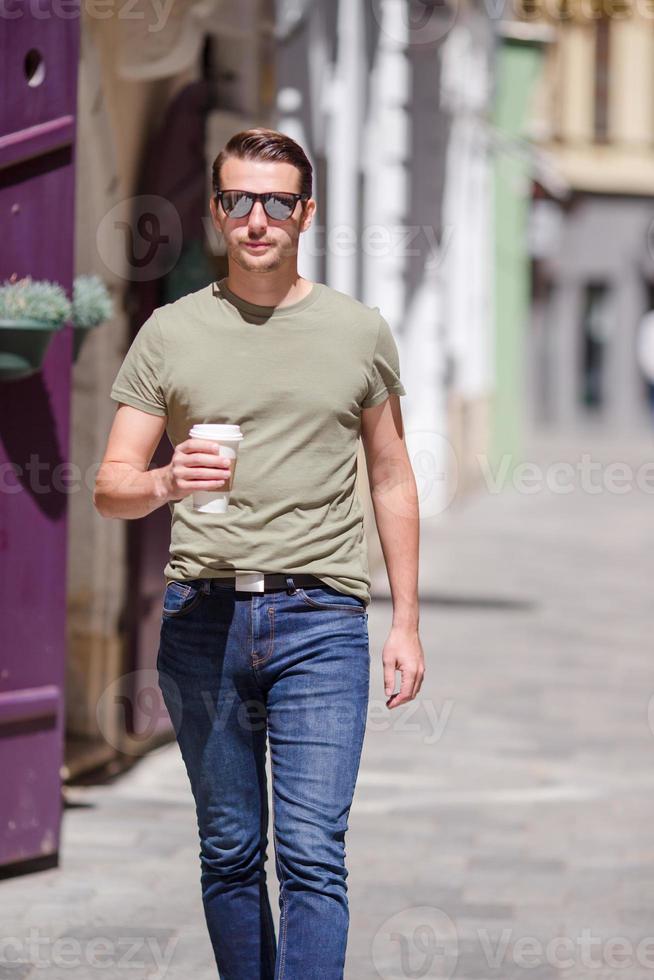 feliz joven hombre urbano bebiendo café en la ciudad europea al aire libre foto