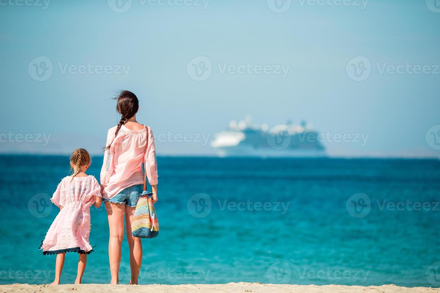 Beautiful mother and daughter at the beach enjoying summer vacation. photo