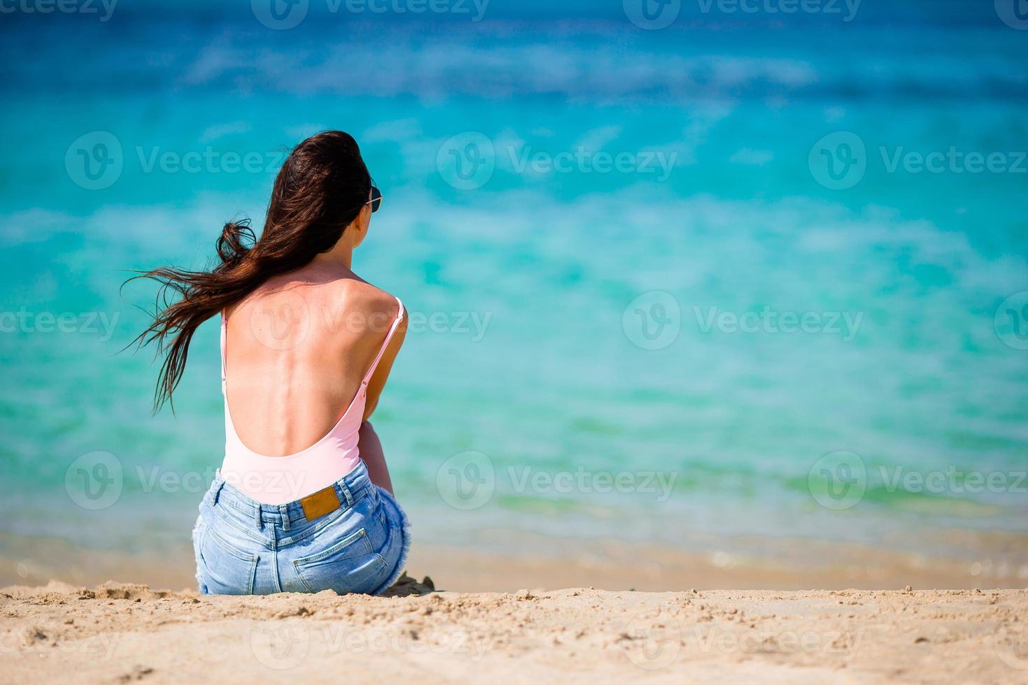 Woman laying on the beach enjoying summer holidays looking at the sea photo