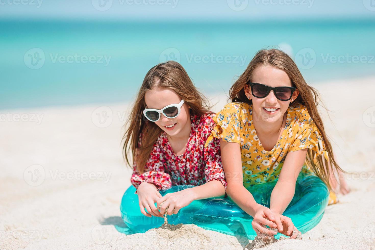 Little happy funny girls have a lot of fun at tropical beach playing together. photo