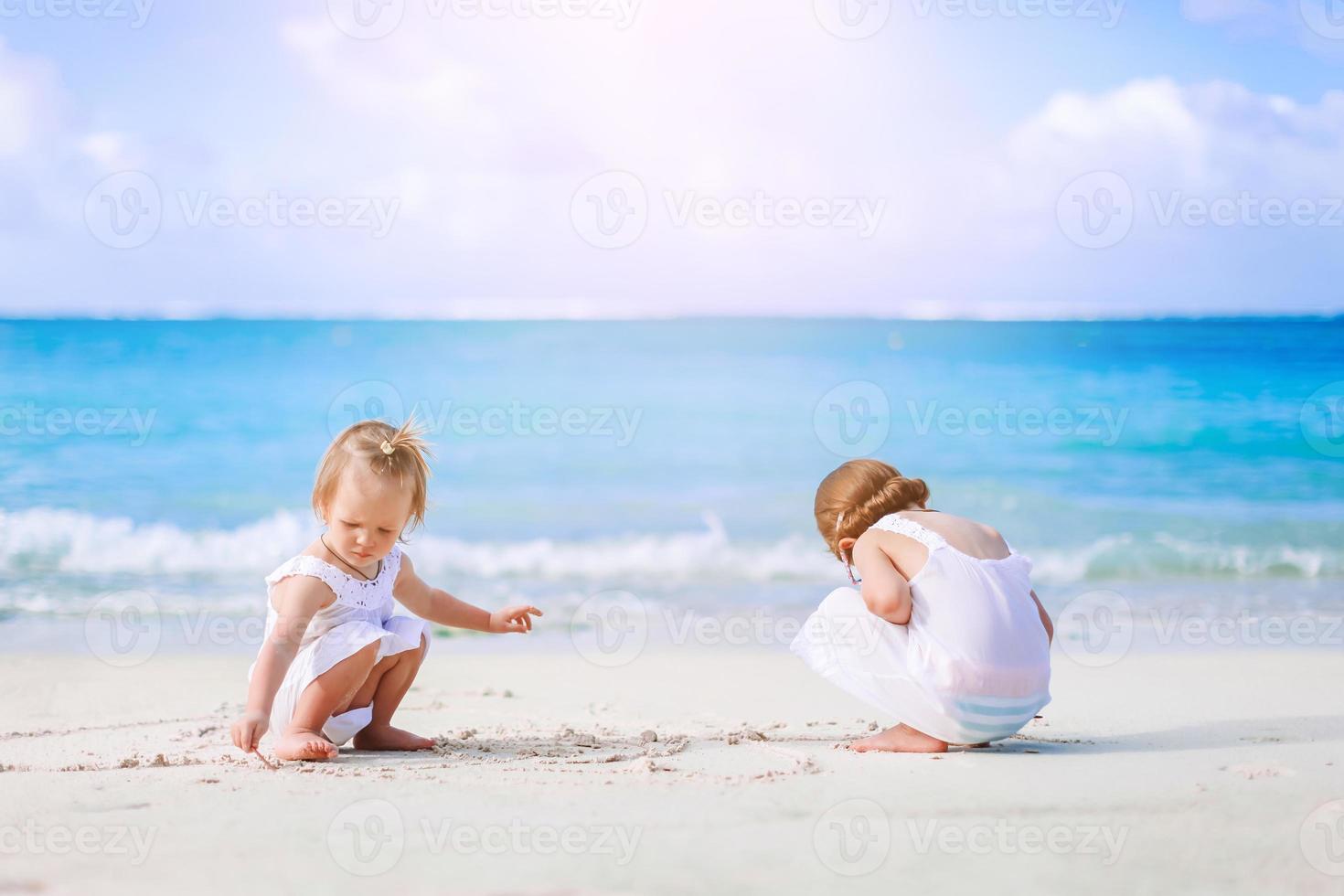 Little happy funny girls have a lot of fun at tropical beach playing together. photo